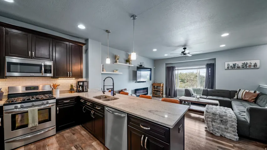 Kitchen featuring dark wood cabinetry, stainless steel appliances, and light-toned countertops