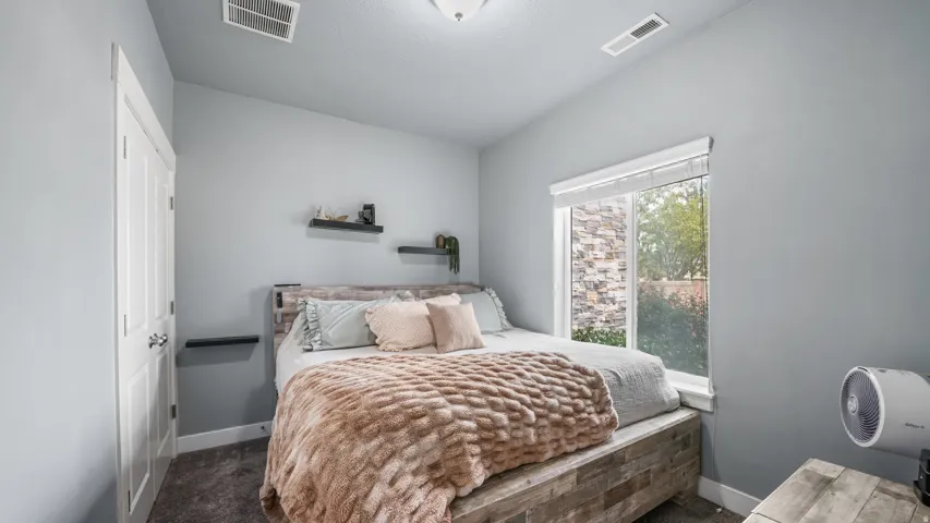Angled ceiling, light gray wall paint, window with white trim, built-in floating shelves, and paneled door