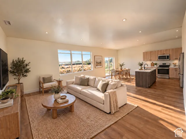Open-concept living space featuring wood-finish flooring, recessed lighting, and large windows
