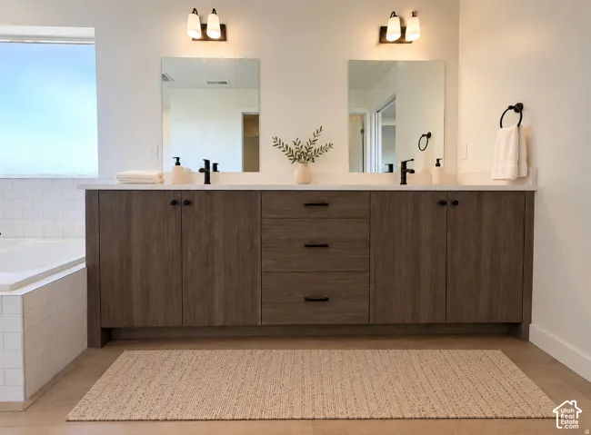 Dual vanity with wood-finish cabinetry, white countertops, and matte black hardware