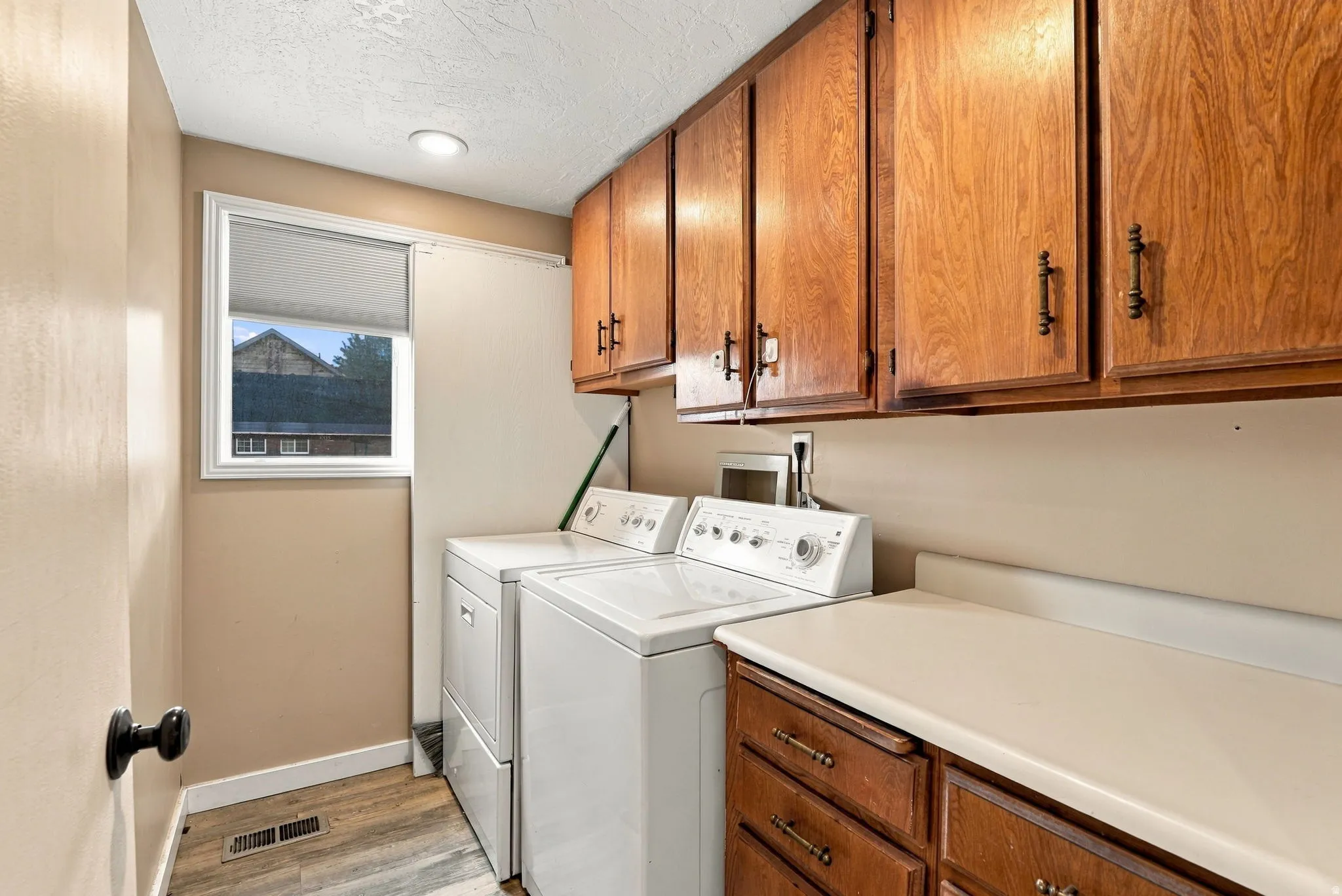 Window with white trim, wood-finish cabinetry, and solid surface countertop