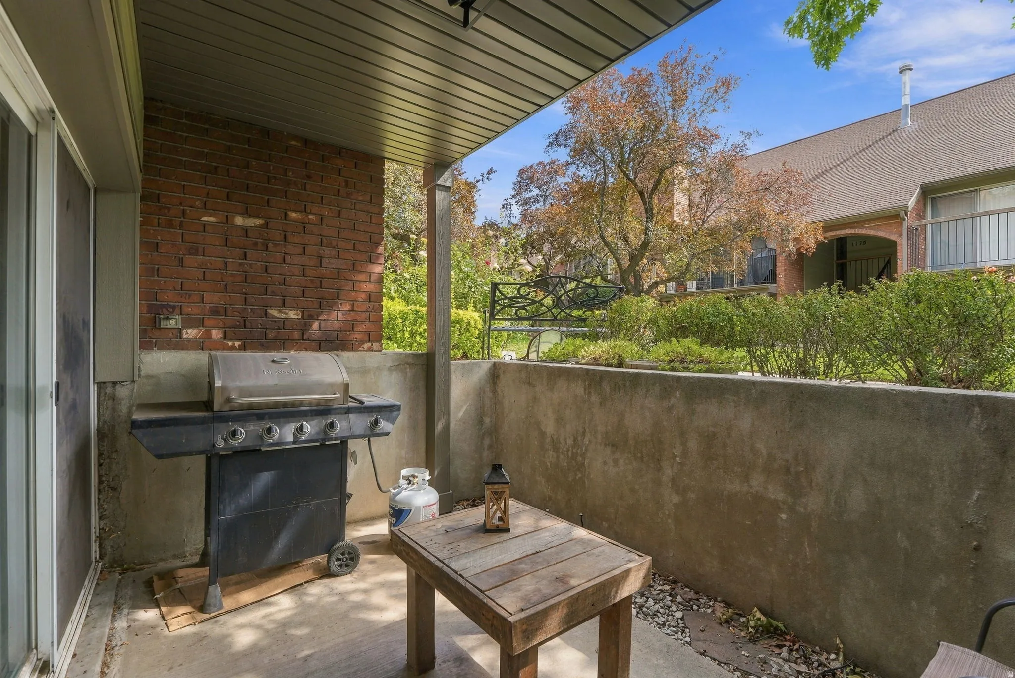 Covered patio featuring concrete flooring and a brick accent wall