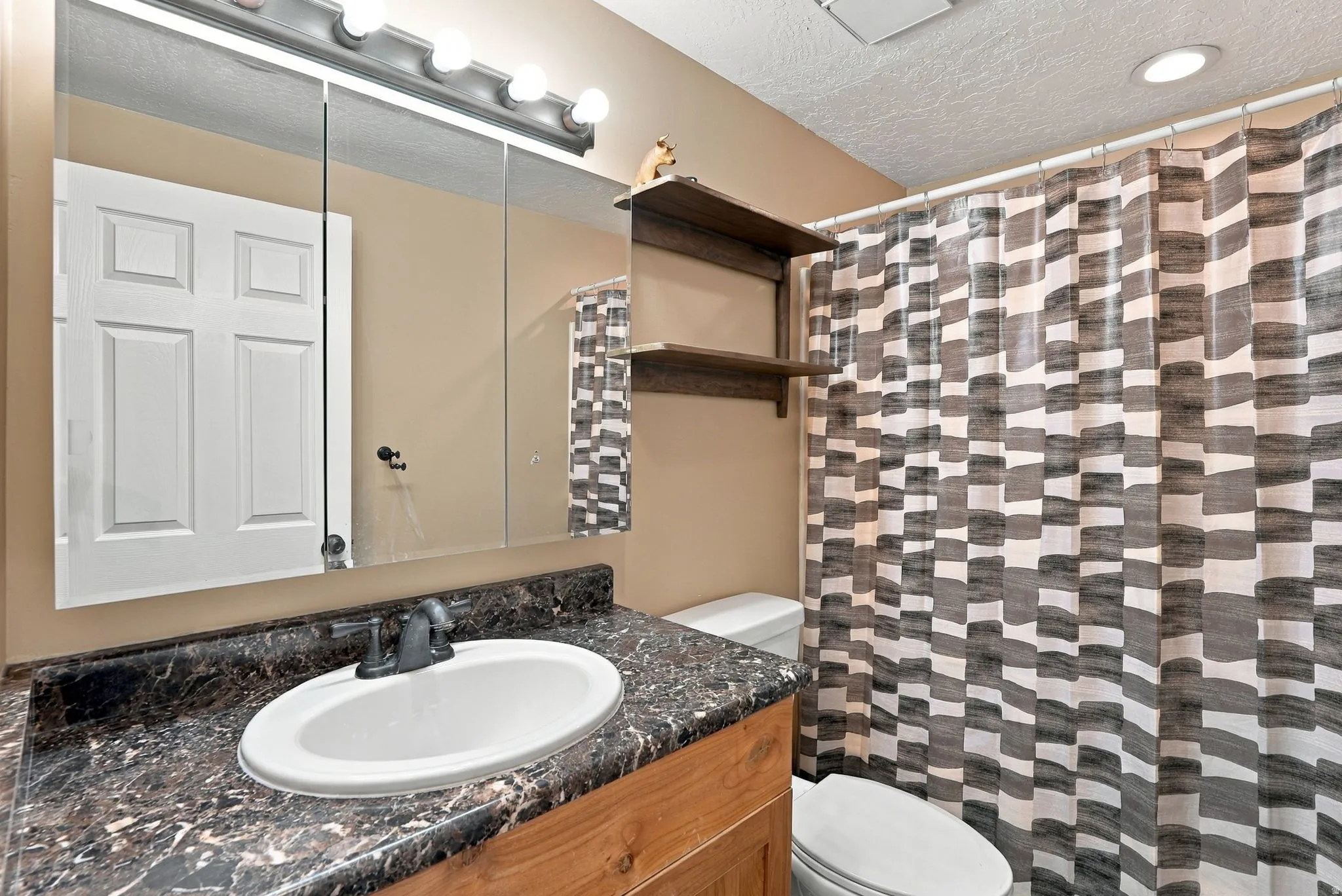 Vanity with an integrated sink, dark countertop, and wood-finish cabinetry