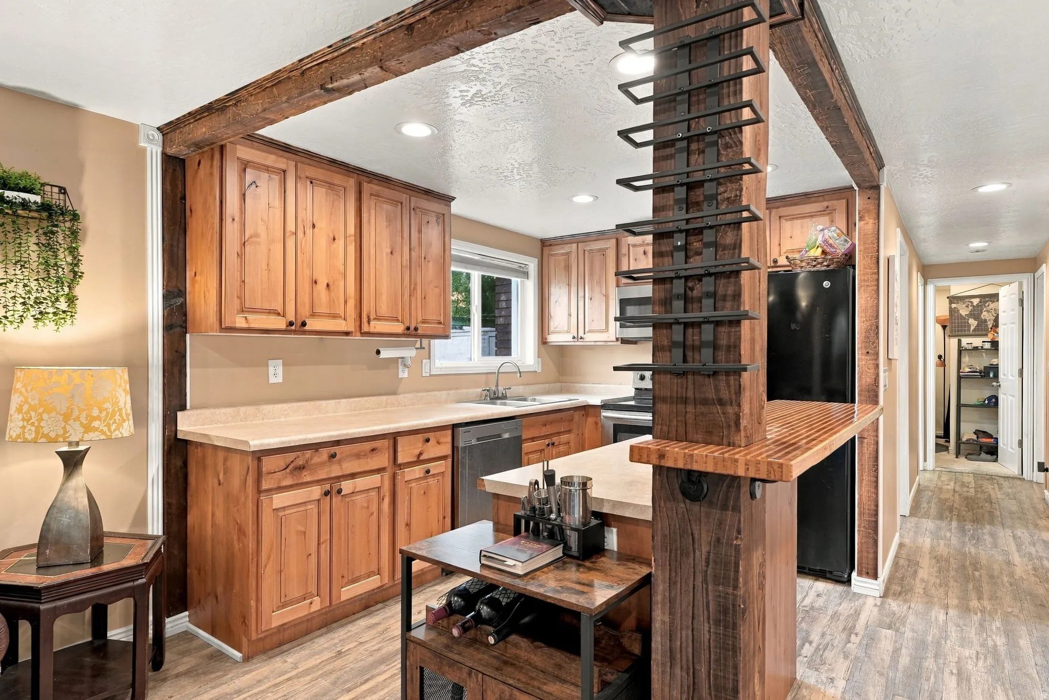 Kitchen featuring wood-finish cabinetry, built-in black appliances, and a wood-finish breakfast bar with an integrated wine rack