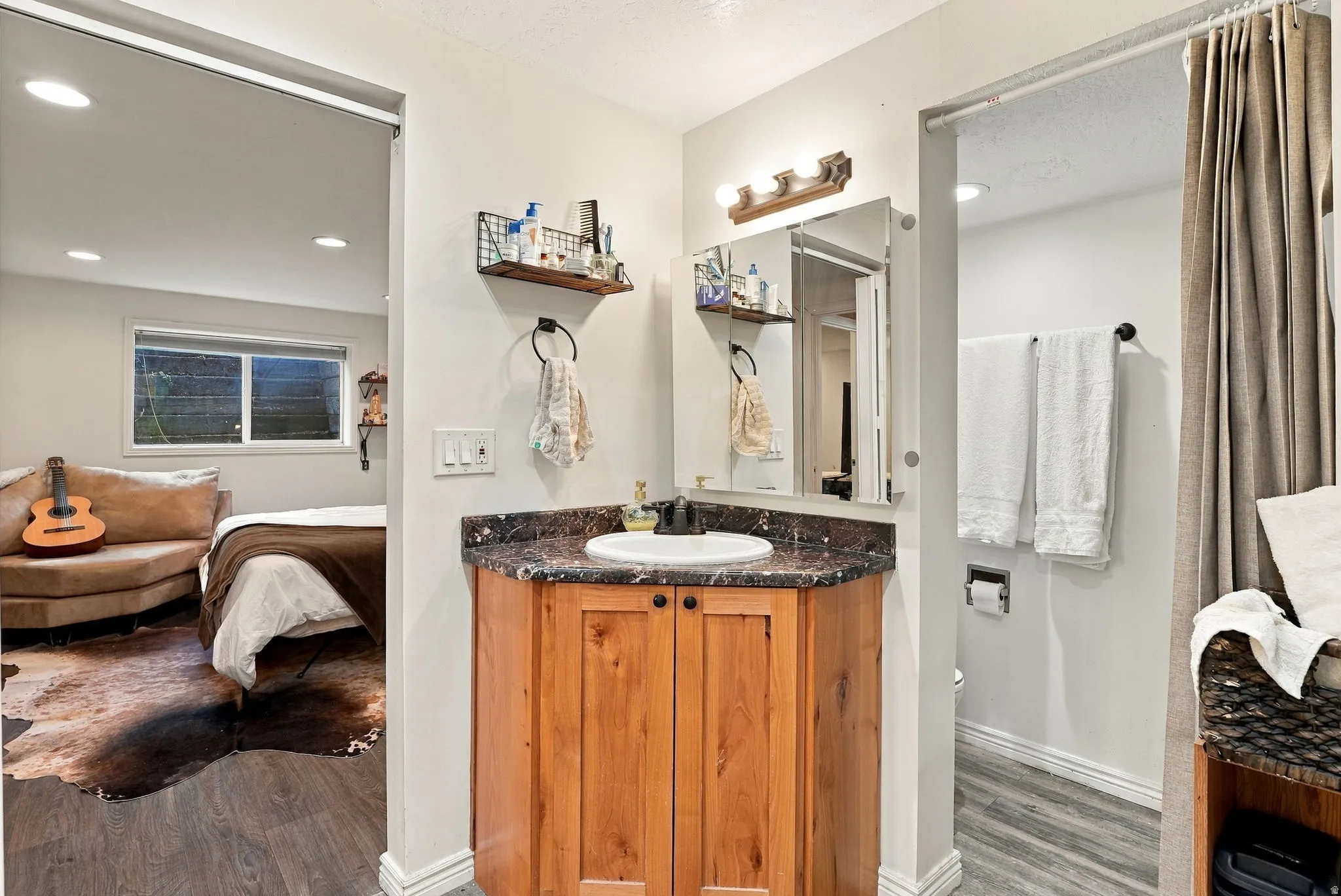 Corner vanity with a dark countertop and undermount sink