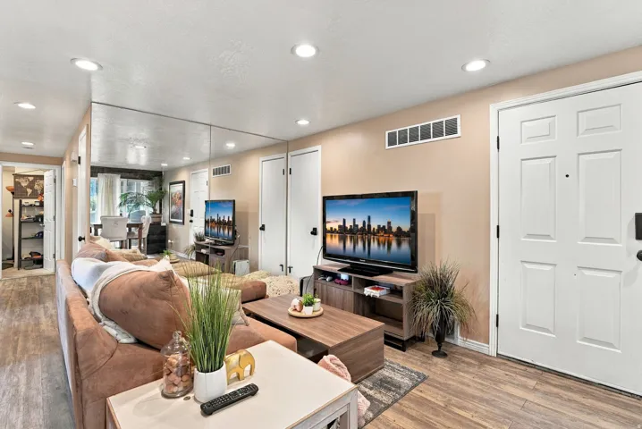Recessed ceiling lighting, wood-finish flooring, mirrored wall accent, white paneled doors, and light neutral wall paint