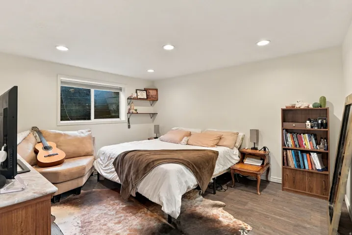 Recessed ceiling lighting, wood-finish flooring, white walls, and a window with white trim