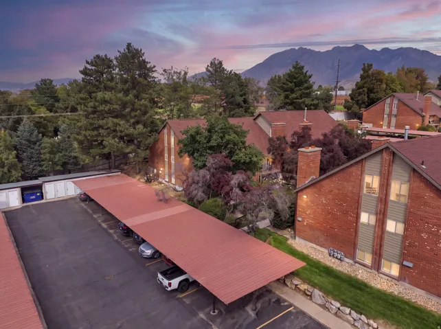 Brick exterior with red shingle roof, covered parking structure, and a mountain backdrop
