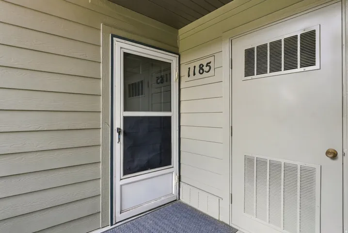 Panel siding exterior with a screen door and an entry door featuring upper and lower louvered panels