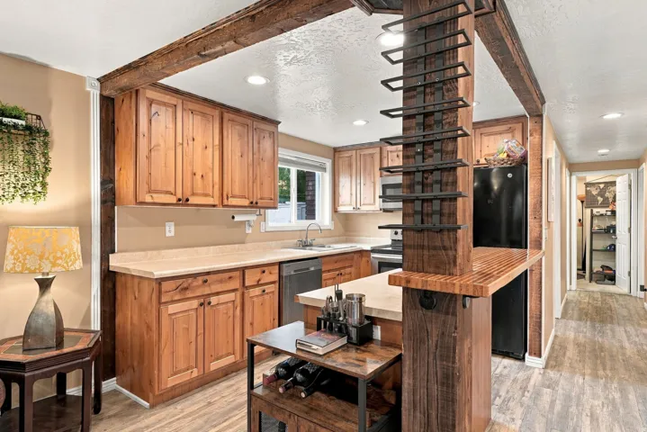 Kitchen featuring wood-finish cabinetry, built-in black appliances, and a wood-finish breakfast bar with an integrated wine rack