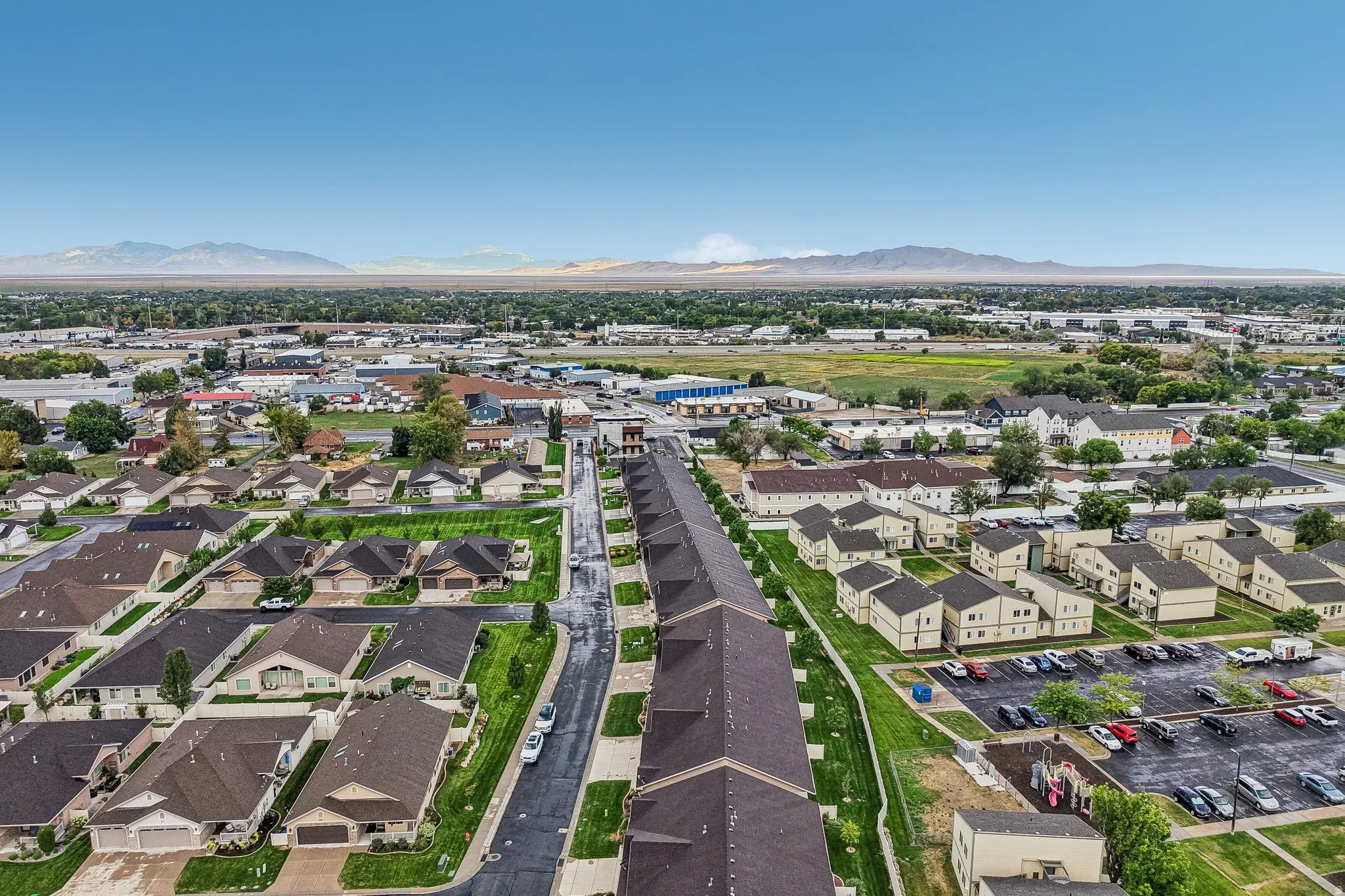 Residential neighborhood with varied architectural styles, asphalt roadways, and mountain backdrop