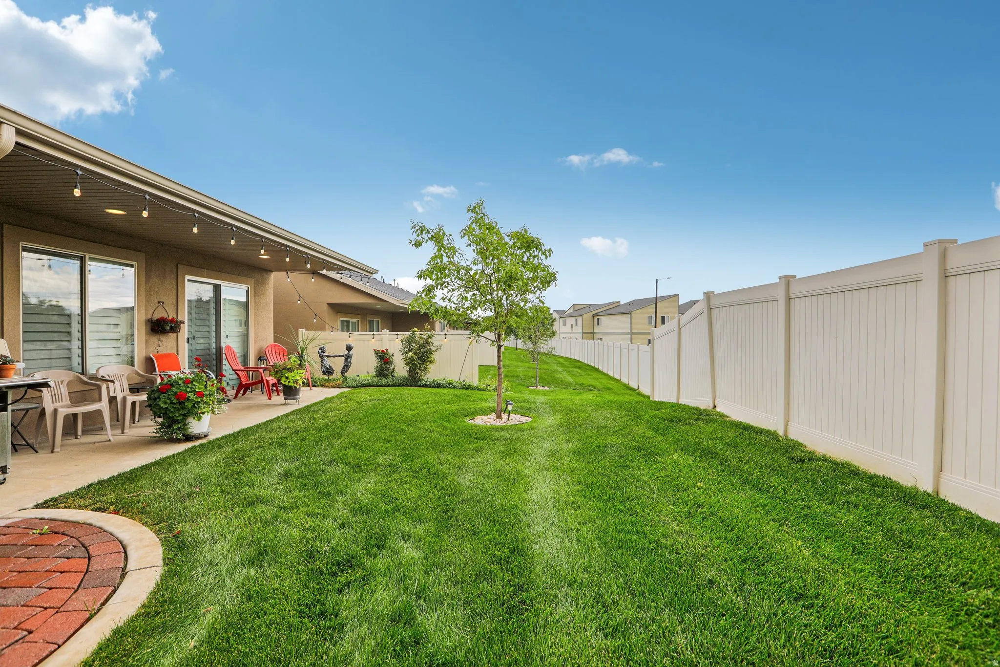 Expansive green lawn, durable vinyl fencing, concrete patio, and direct access through sliding glass doors