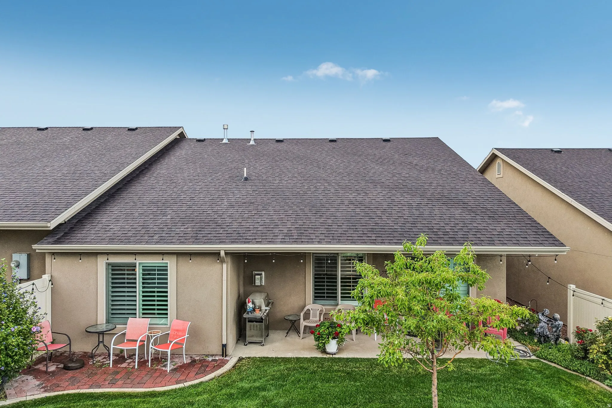 Expansive grassy area featuring a paved patio and a covered outdoor living space