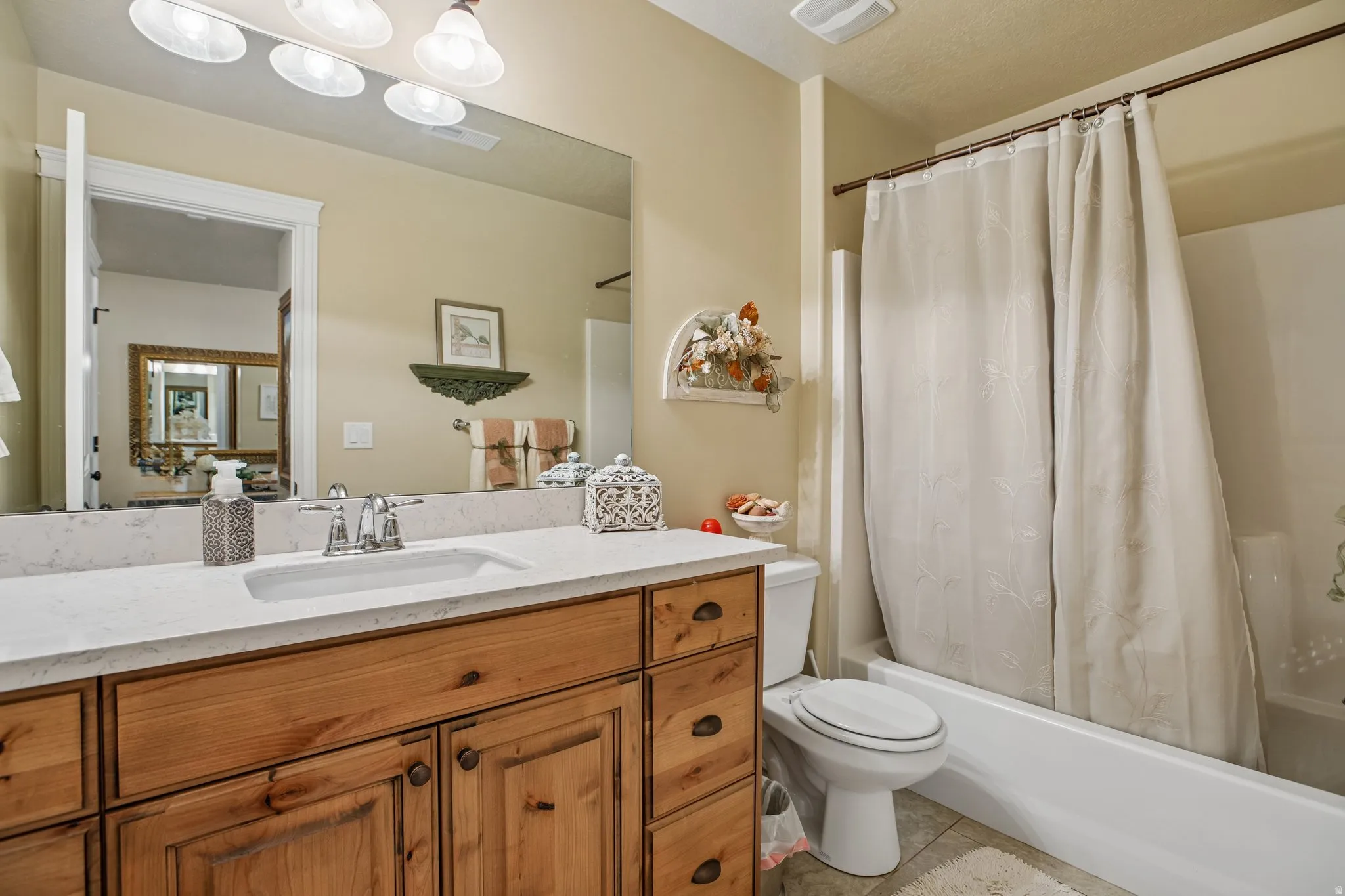 Wood-finish vanity with an integrated sink and chrome faucet, set beneath a large wall-mounted mirror