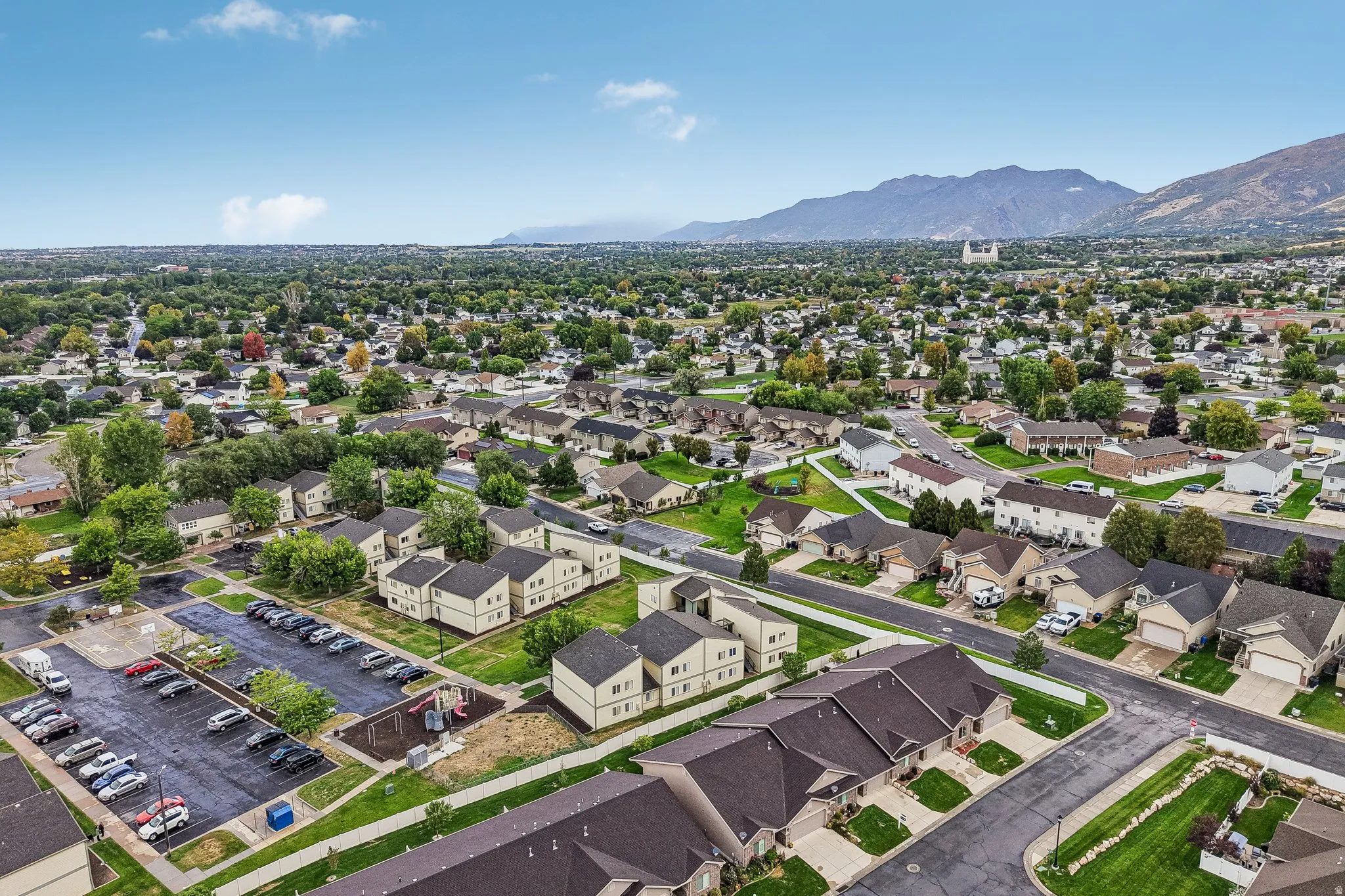 Aerial perspective highlighting a residential community with varied architectural styles, mature trees, and mountainous terrain in the background