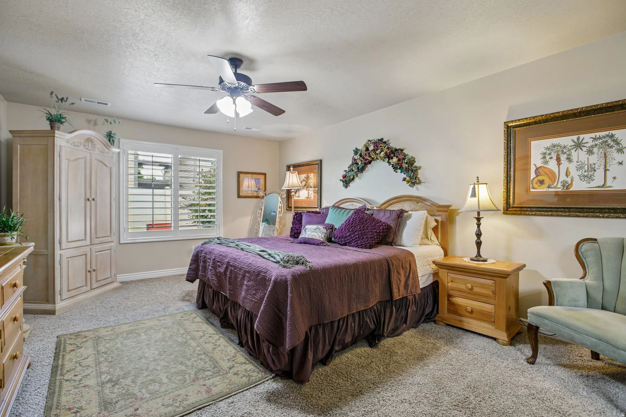 Bedroom featuring a ceiling fan, white window shutters, and soft carpeting