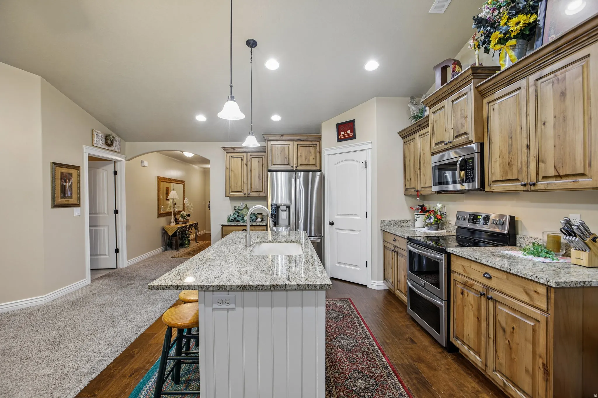 Kitchen featuring a center island with pendant lighting, stone countertops, stainless steel appliances, and wood-finish cabinetry