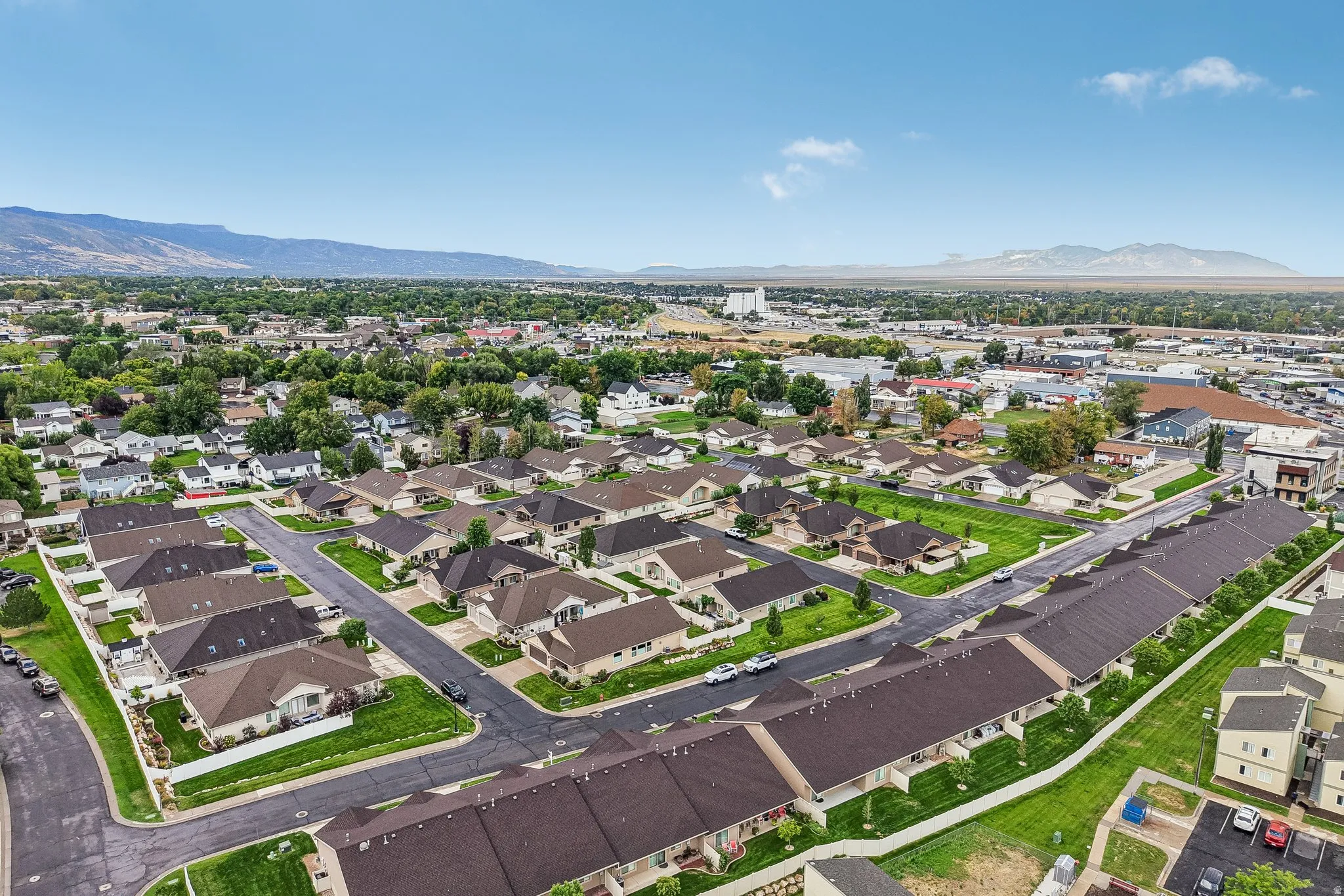 Residential development with a mix of single-family homes and multi-story townhomes, featuring paved streets and manicured green spaces