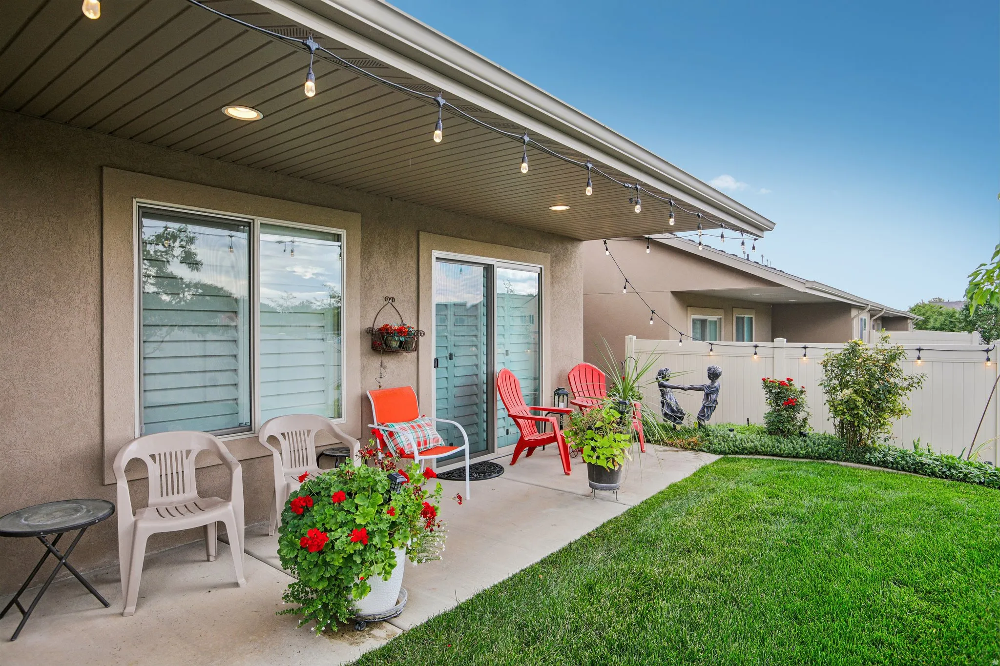 Private concrete patio with a manicured lawn, string lighting, and a privacy fence