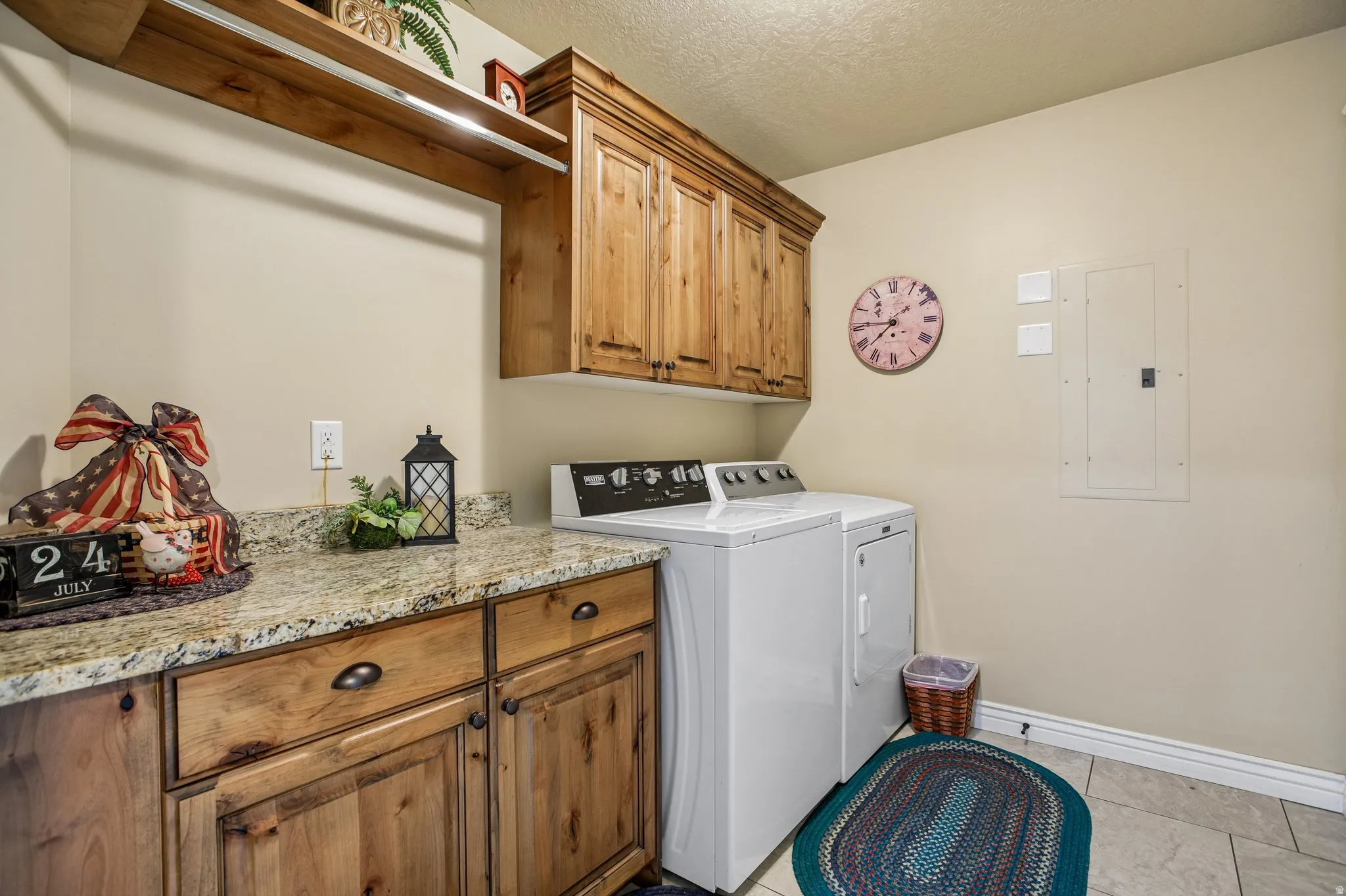 Laundry area featuring wood-finish cabinetry, a stone-finish countertop, and tile flooring