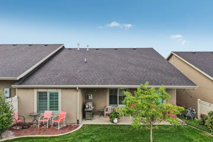 Expansive grassy area featuring a paved patio and a covered outdoor living space