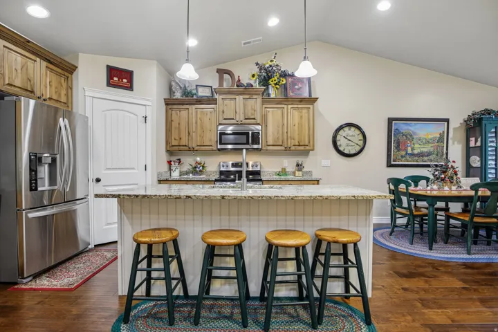 Kitchen featuring wood-finish cabinetry, stainless steel appliances, a center island with granite countertops, and recessed lighting