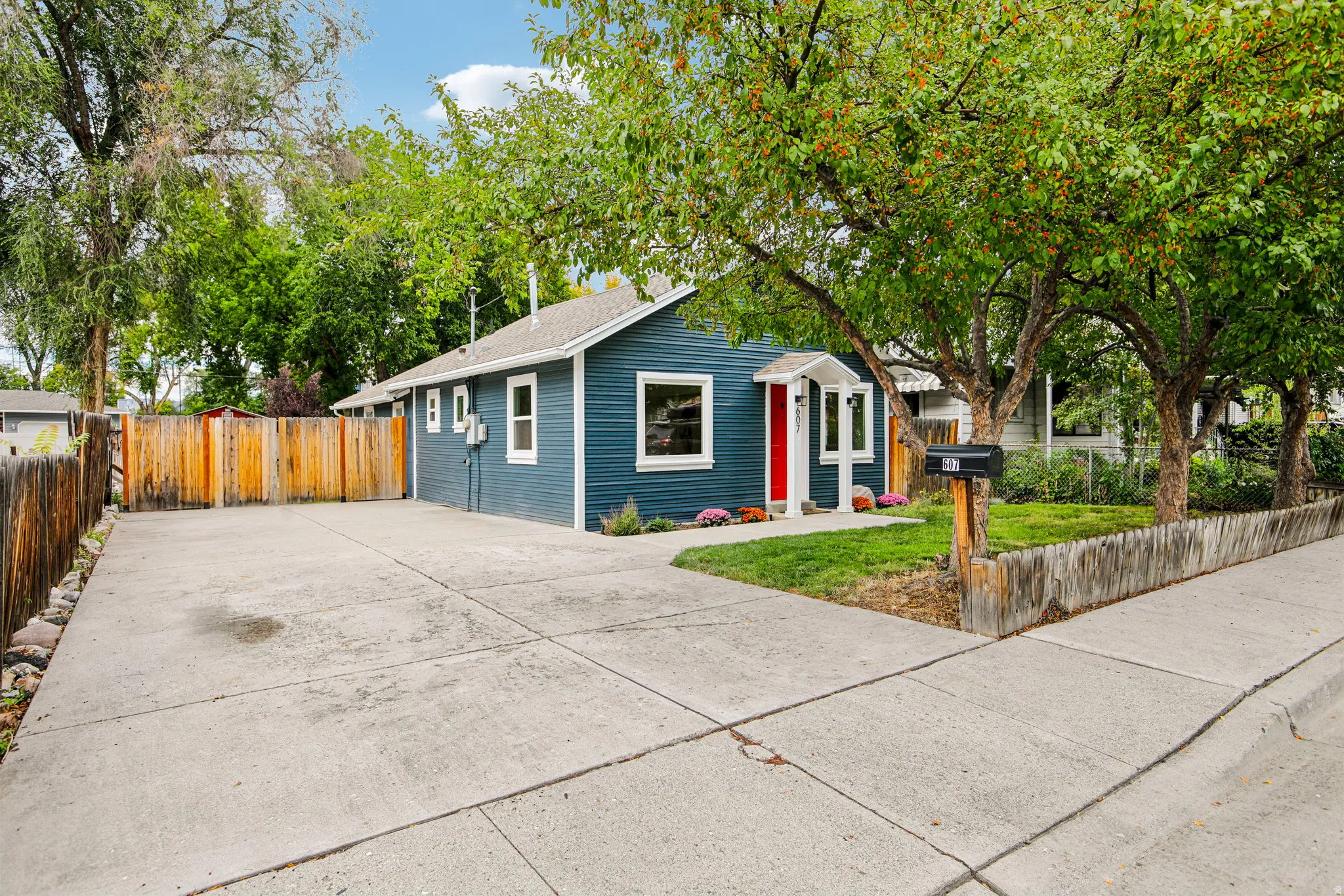 Blue siding exterior with white trim, red front door, and a concrete driveway