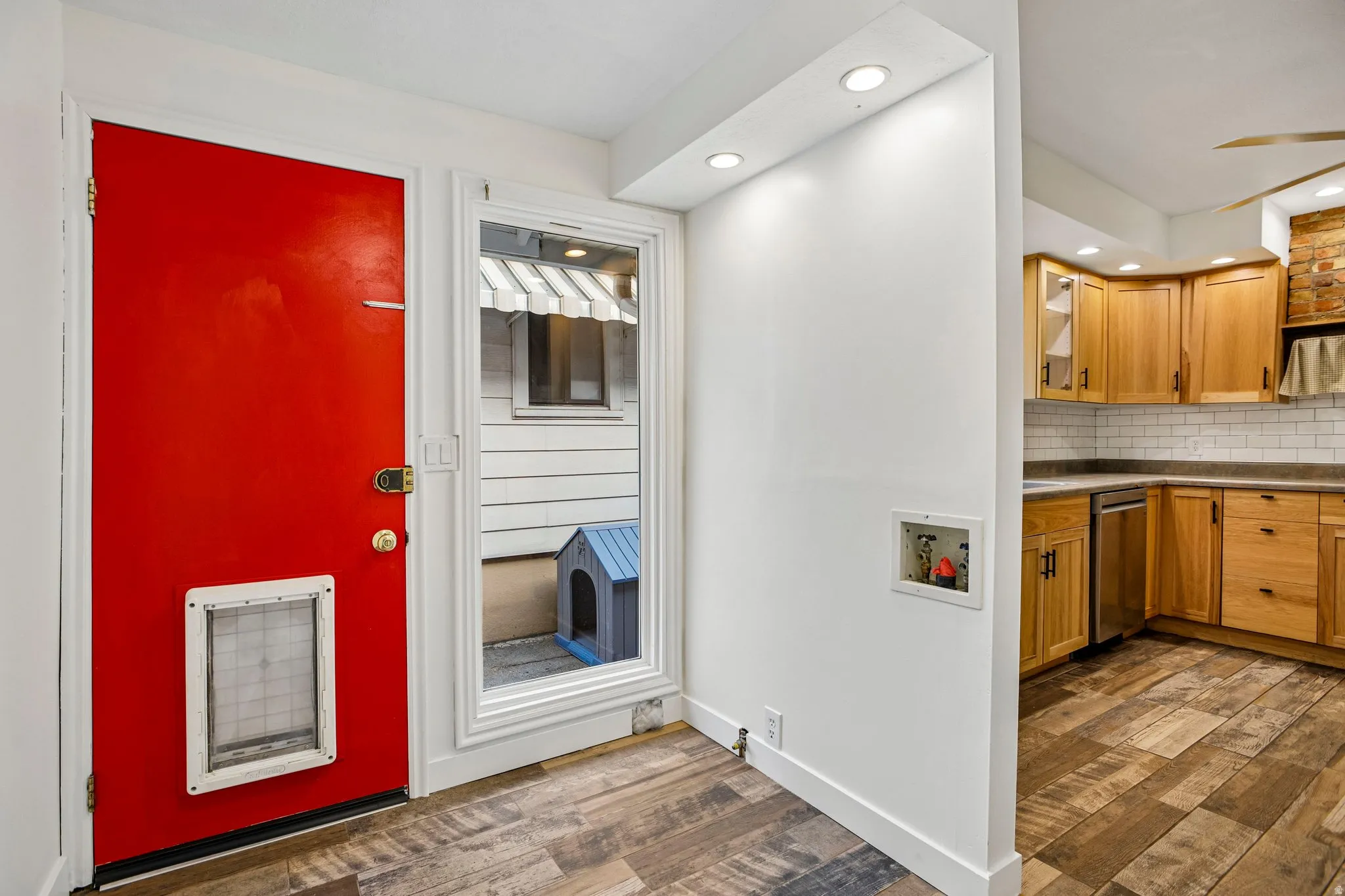 Wood-finish flooring throughout, bright recessed lighting, and a white subway tile backsplash