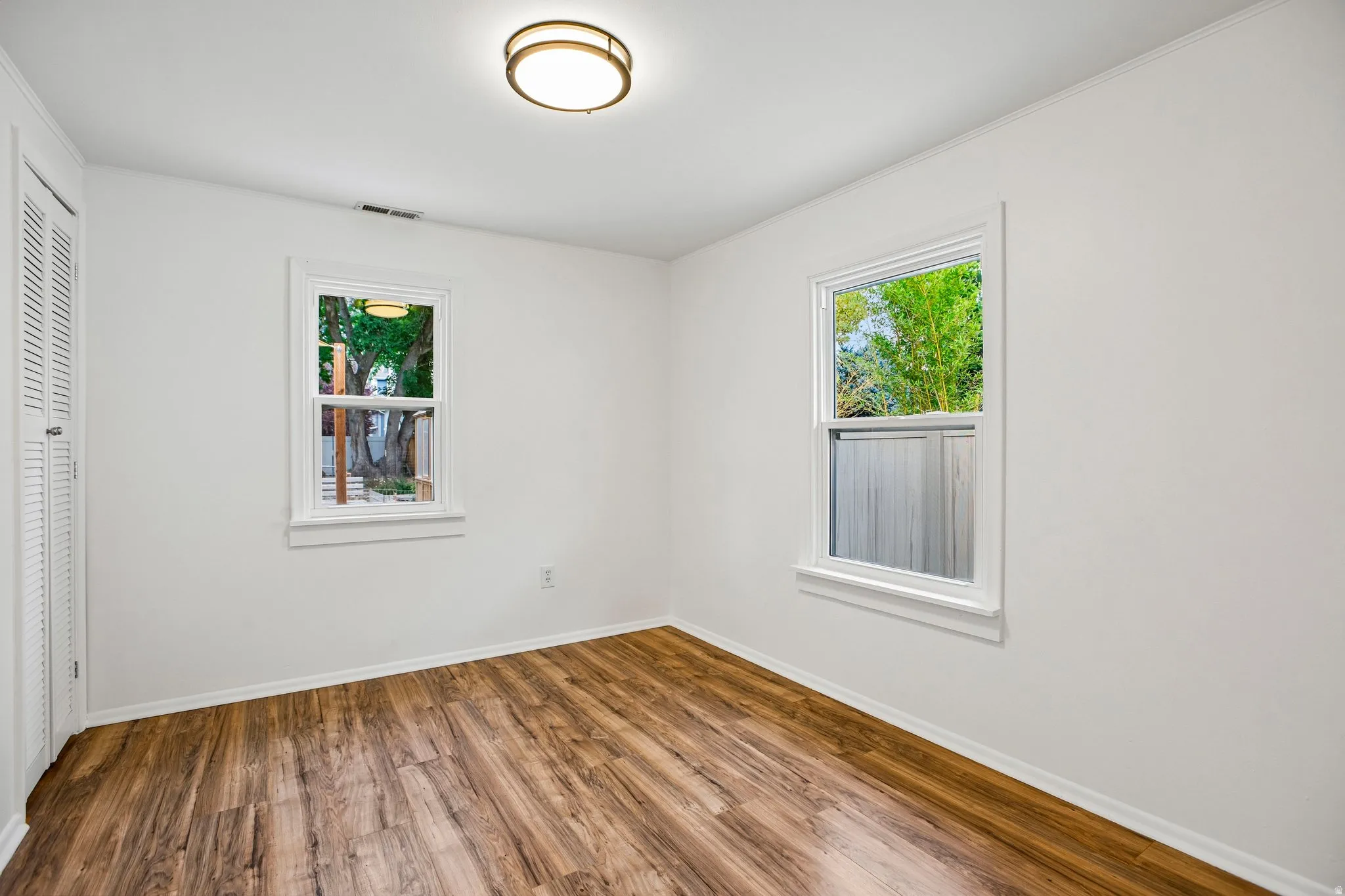 Wood-finish flooring, white walls, and a contemporary flush-mount ceiling light