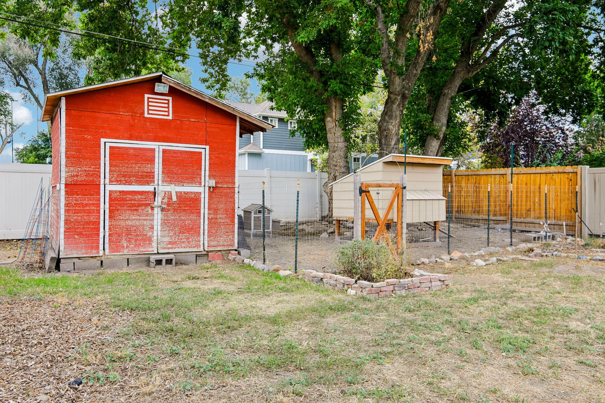 Red painted storage shed, dedicated garden area, wood-finish privacy fencing, and mature trees