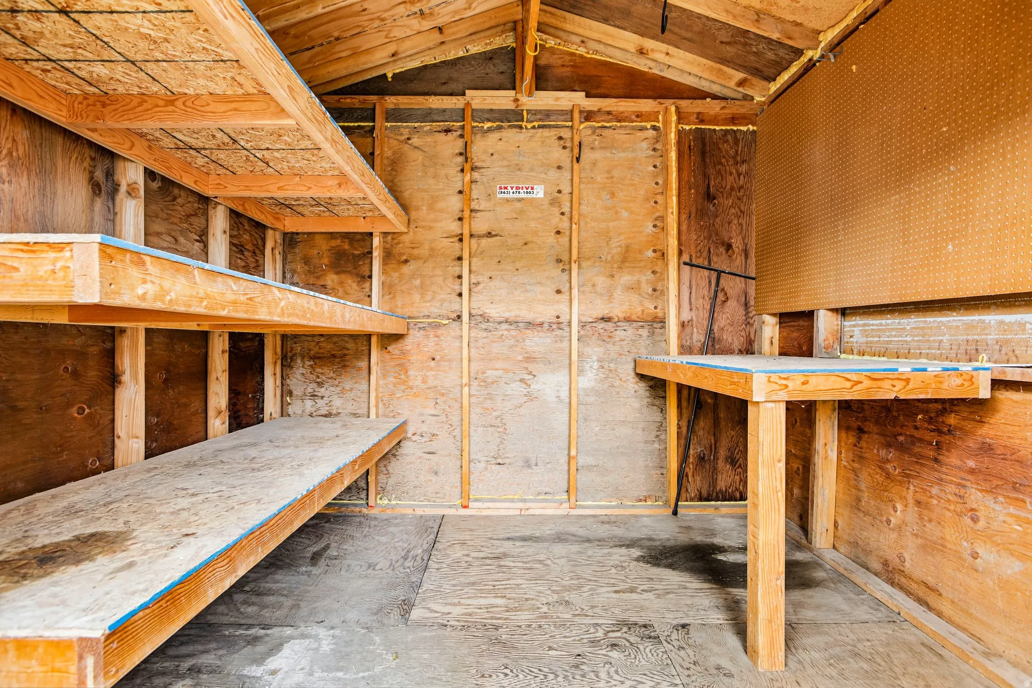 Wood-paneled interior featuring built-in shelving, a wood-finish workbench, and a pegboard wall