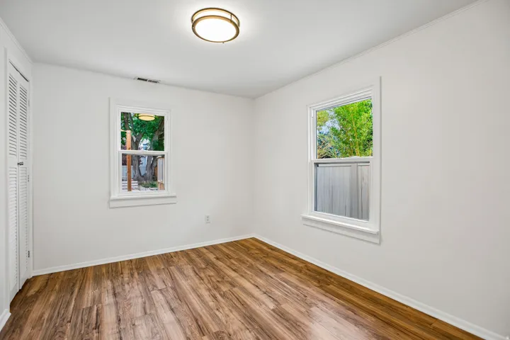 Wood-finish flooring, white walls, and a contemporary flush-mount ceiling light