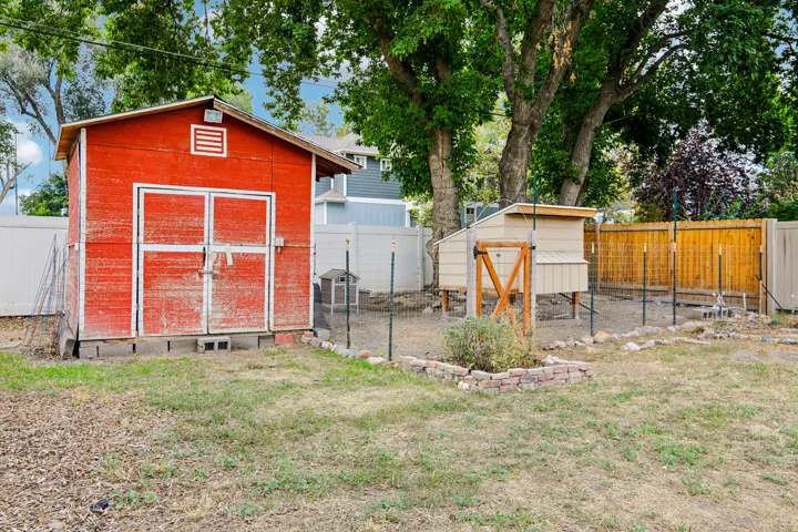 Red painted storage shed, dedicated garden area, wood-finish privacy fencing, and mature trees
