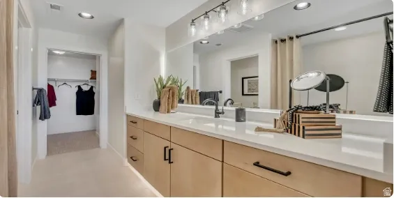 Expansive vanity with light wood-finish cabinetry, a white countertop, and a large wall-mounted mirror. This home is under construction. Pictures are of a similar home.