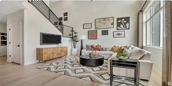 High ceilings, light wood-finish flooring, and a contemporary metal staircase with horizontal balusters complement the bright, neutral wall finishes and large window. This home is under construction. Pictures are of a similar home.