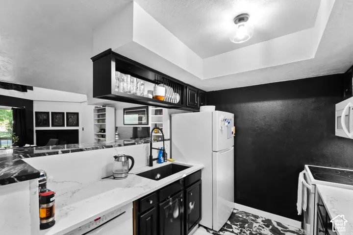 Kitchen featuring black cabinetry, white countertops with veining, black composite sink with a matte black faucet, and black and white patterned flooring