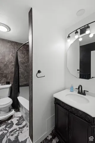 Black and white patterned tile flooring with a traditional dark wood vanity, white countertop, and black fixtures