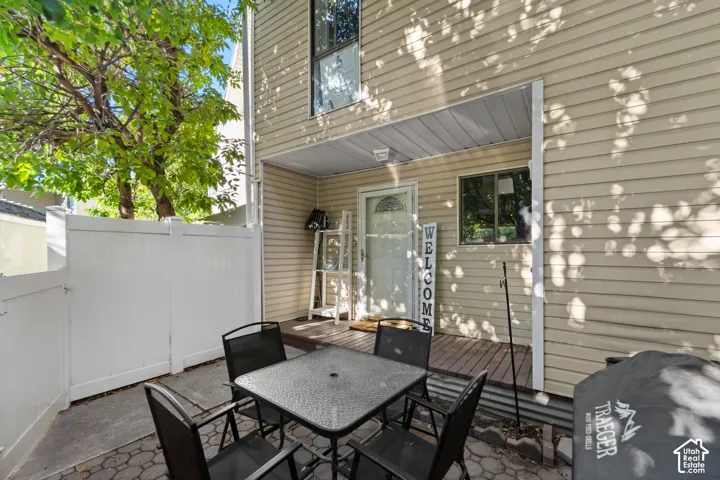 Patio area featuring paver flooring, white privacy fencing, and a covered porch with a wood-finish deck