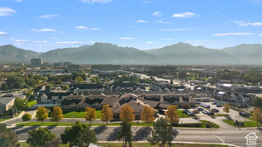 Expansive mountain range backdrop, urban setting with diverse architecture, and established trees