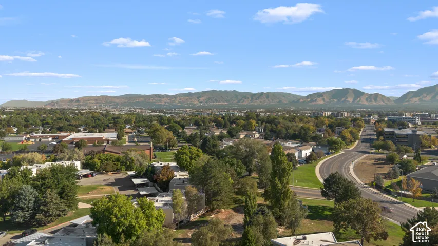 Expansive residential area with mature tree coverage, a clear road network, and distant mountain backdrops
