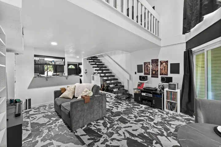 High ceilings with an open loft space, patterned tile flooring,  and a sliding glass door providing access to the exterior