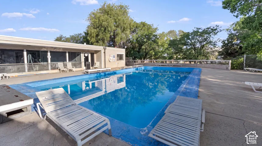 Rectangular swimming pool with a concrete surround, enclosed by a perimeter fence