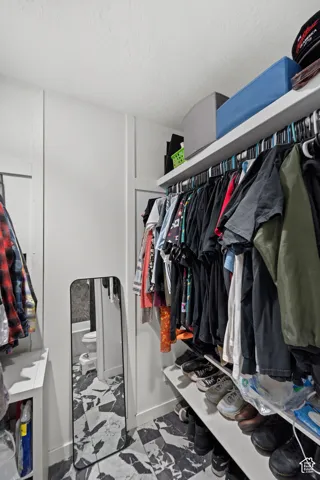 Walk-in closet with integrated shelving, multiple hanging rods, and patterned flooring
