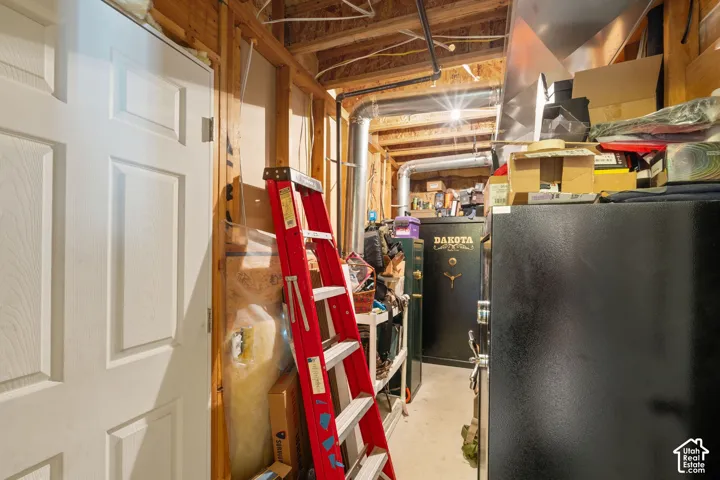 Unfinished utility area featuring exposed timber framing, exposed mechanical ductwork, and a paneled interior door