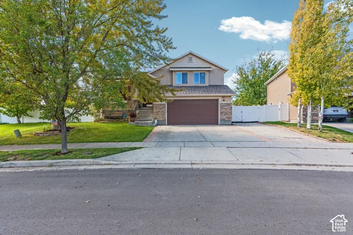 Two-story exterior featuring stone veneer accents, an attached two-car garage, and concrete driveway with decorative paver borders