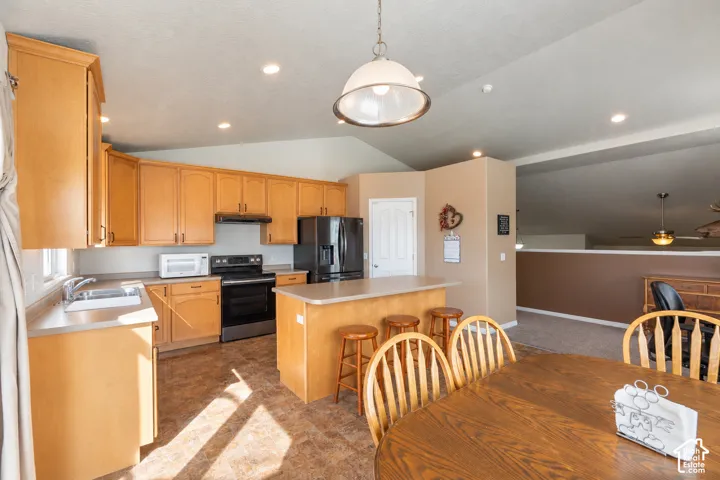 Kitchen featuring light-finish cabinetry, a central island with counter seating, vaulted ceilings, recessed lighting, and a metal-finish pendant light