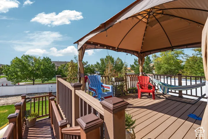 Elevated deck featuring composite decking, matching railings, and a built-in metal-framed gazebo