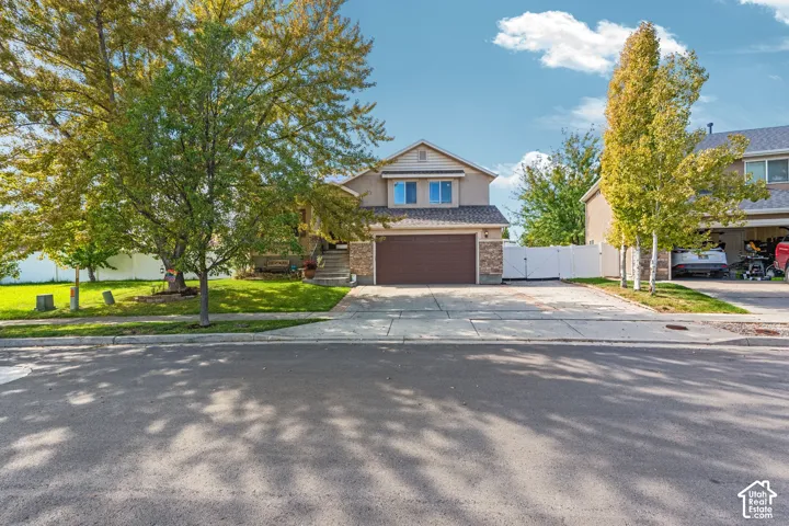 Exterior featuring stone veneer accents, stucco siding, a two-car garage, and concrete driveway