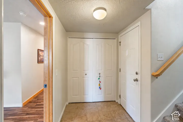 Entryway featuring tile flooring, six-panel closet doors, flush-mount lighting, and a wood-finish handrail