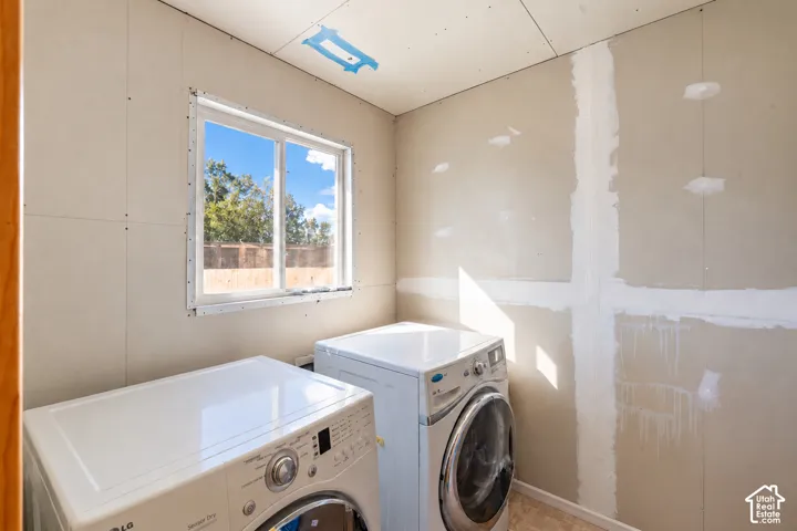 Sliding window with natural light, unfinished drywall walls, and installed laundry appliances